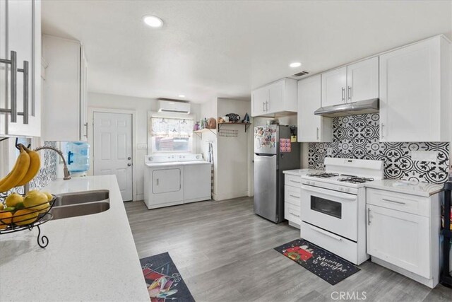 2838 N G St, San Bernardino, CA 92405 - kitchen featuring white gas range, freestanding refrigerator, washer and clothes dryer, under cabinet range hood, and a wall mounted AC