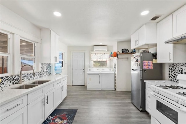 2838 N G St, San Bernardino, CA 92405 - kitchen featuring washing machine and dryer, white range with gas stovetop, a wall mounted air conditioner, backsplash, and light countertops