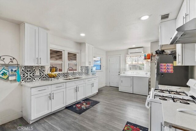 2838 N G St, San Bernardino, CA 92405 - kitchen with washer and dryer, gas range gas stove, exhaust hood, an AC wall unit, and fridge