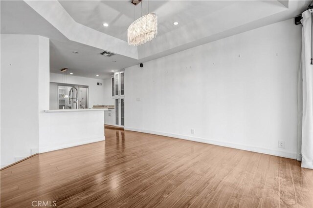 5333 Zelzah Ave Unit 203, Encino, CA 91316 - unfurnished living room featuring a tray ceiling, wood finished floors, a chandelier, and recessed lighting