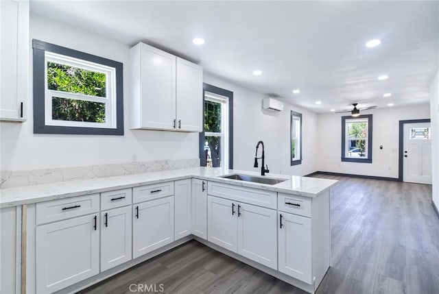 1235 Spruce St, San Bernardino, CA 92411 - kitchen featuring a wall mounted air conditioner, a peninsula, wood finished floors, recessed lighting, and white cabinetry