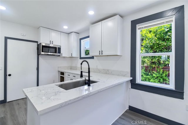 1235 Spruce St, San Bernardino, CA 92411 - kitchen with stainless steel microwave, light wood finished floors, a peninsula, plenty of natural light, and recessed lighting