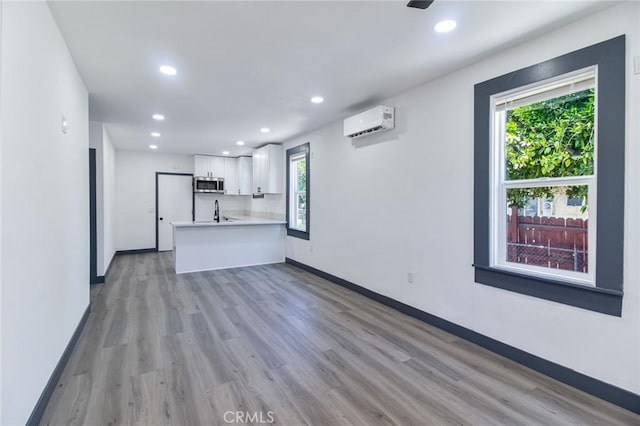 1235 Spruce St, San Bernardino, CA 92411 - unfurnished living room with a wall unit AC, plenty of natural light, recessed lighting, and light wood-type flooring