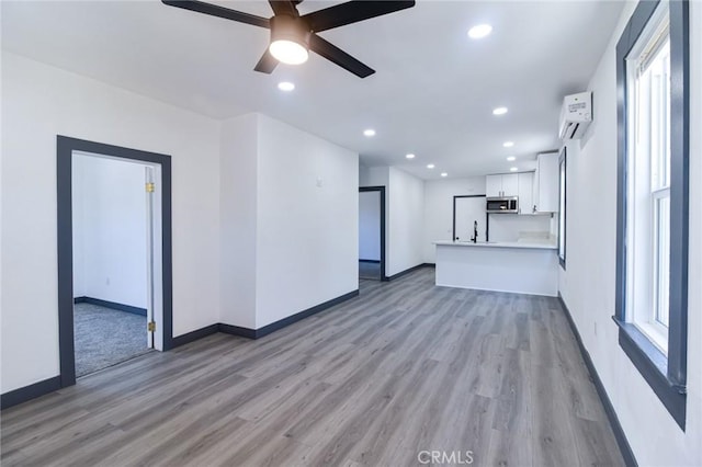 1235 Spruce St, San Bernardino, CA 92411 - unfurnished living room with light wood-type flooring, a wall mounted AC, a ceiling fan, and recessed lighting