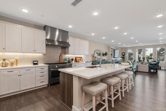 800 Grand Ave Unit 105, Carlsbad, CA 92008 - kitchen featuring stainless steel range, wall chimney exhaust hood, dark wood-style floors, a breakfast bar area, and decorative backsplash