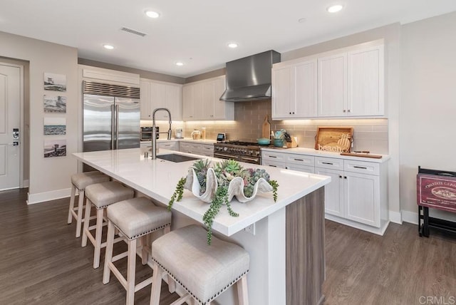 800 Grand Ave Unit 105, Carlsbad, CA 92008 - kitchen with wall chimney range hood, high quality appliances, dark wood-style floors, white cabinets, and a kitchen bar