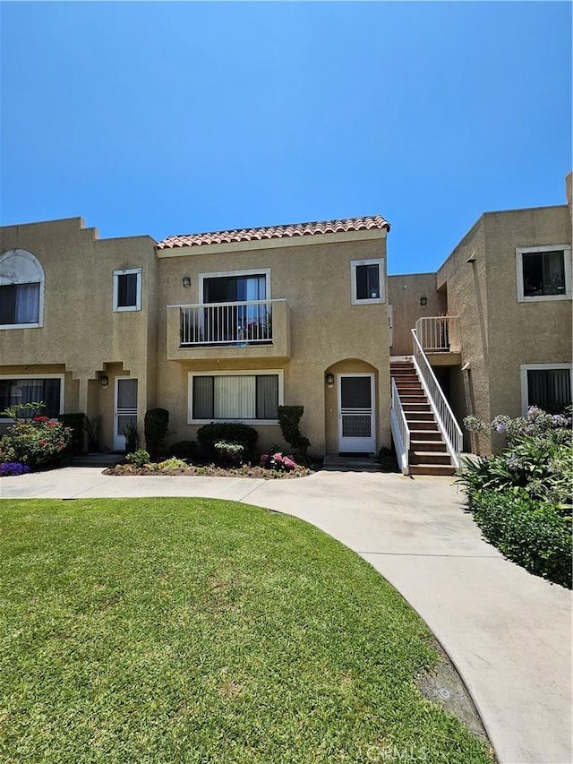 13171 Newland St Unit 11, Garden Grove, CA 92844 - view of front facade with stucco siding, stairway, a front lawn, and a tile roof