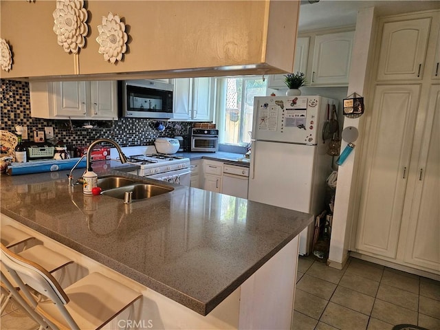 13171 Newland St Unit 11, Garden Grove, CA 92844 - kitchen with white appliances, light tile patterned floors, a peninsula, decorative backsplash, and a kitchen breakfast bar