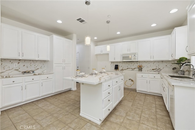 17129 Lacebark St, Fontana, CA 92337 - kitchen featuring white microwave, backsplash, recessed lighting, hanging light fixtures, and white cabinetry