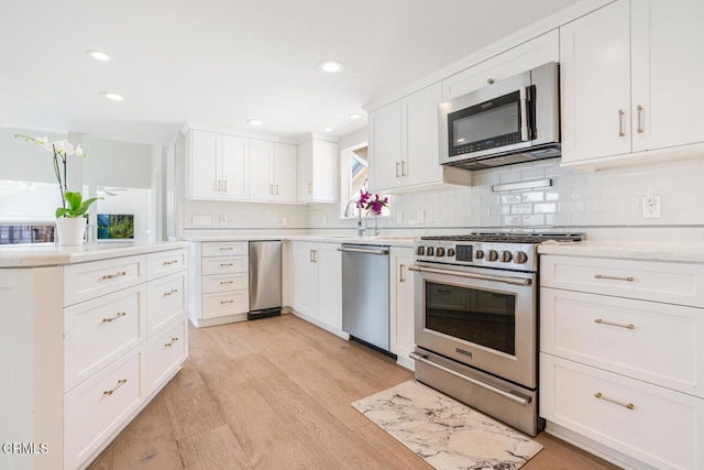 5040 Island View St, Oxnard, CA 93035 - kitchen featuring stainless steel appliances, light countertops, light wood-type flooring, tasteful backsplash, and white cabinetry
