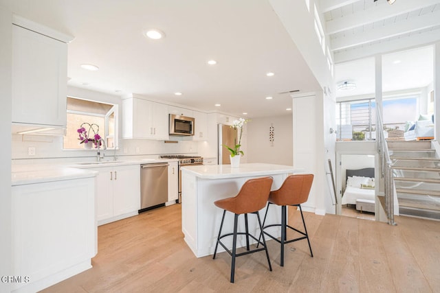 5040 Island View St, Oxnard, CA 93035 - kitchen with stainless steel appliances, light wood-type flooring, white cabinetry, a center island, and a kitchen bar