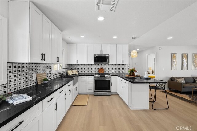 5676 Aztec Ave Unit 29, Palms, CA 92277 - kitchen with stainless steel appliances, open floor plan, light wood-style floors, a kitchen bar, and white cabinetry