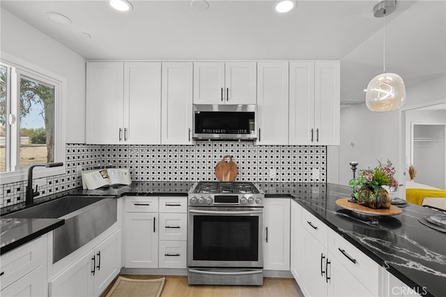 5676 Aztec Ave Unit 29, Palms, CA 92277 - kitchen featuring appliances with stainless steel finishes, white cabinetry, recessed lighting, dark stone counters, and decorative backsplash