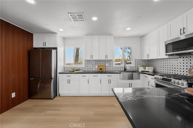 5676 Aztec Ave Unit 29, Palms, CA 92277 - kitchen with stainless steel appliances, decorative backsplash, white cabinets, light wood-style flooring, and recessed lighting
