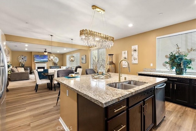 4106 Irish Moss Ln, San Bernardino, CA 92407 - kitchen featuring open floor plan, light wood-style flooring, a fireplace, a center island with sink, and decorative light fixtures