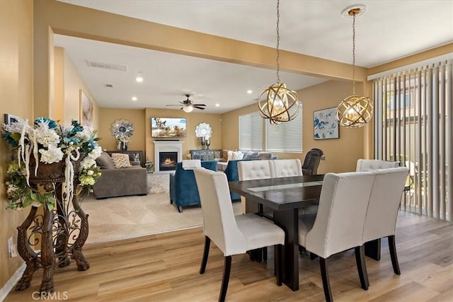 4106 Irish Moss Ln, San Bernardino, CA 92407 - dining space featuring healthy amount of natural light, light wood-type flooring, a ceiling fan, a lit fireplace, and recessed lighting