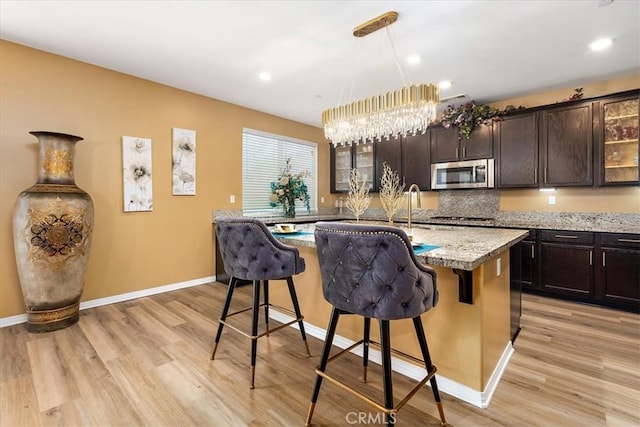4106 Irish Moss Ln, San Bernardino, CA 92407 - kitchen with stainless steel appliances, light wood-type flooring, a kitchen breakfast bar, dark brown cabinetry, and recessed lighting