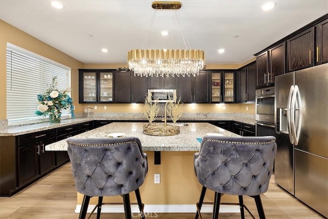 4106 Irish Moss Ln, San Bernardino, CA 92407 - kitchen with stainless steel appliances, a center island with sink, light wood-type flooring, a breakfast bar area, and recessed lighting