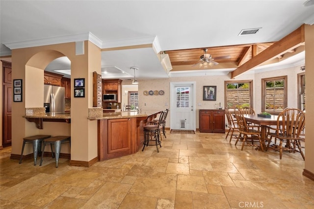 25572 Orchard Rim Ln, Lake Forest, CA 92630 - kitchen with stainless steel appliances, stone tile flooring, a kitchen breakfast bar, ornamental molding, and brown cabinetry