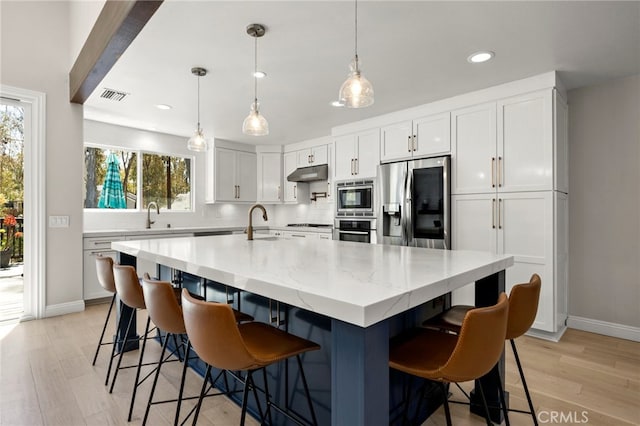 24932 Dove Tree Ln, Lake Forest, CA 92630 - kitchen featuring under cabinet range hood, appliances with stainless steel finishes, recessed lighting, light wood-style flooring, and tasteful backsplash