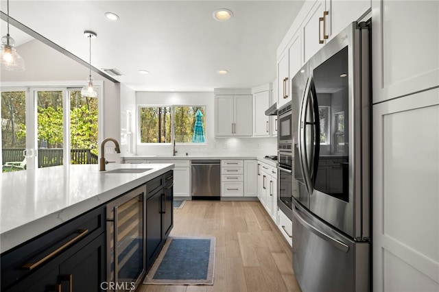 24932 Dove Tree Ln, Lake Forest, CA 92630 - kitchen featuring stainless steel appliances, wine cooler, white cabinetry, light wood finished floors, and recessed lighting