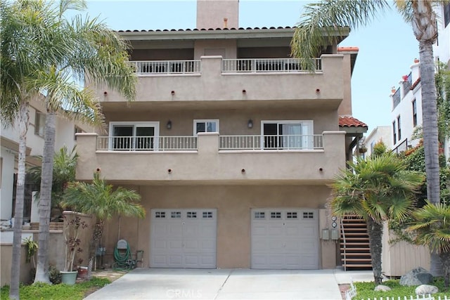 518 Avenida Victoria Unit A, San Clemente, CA 92672 - view of front of home with an attached garage, concrete driveway, stucco siding, a balcony, and stairs