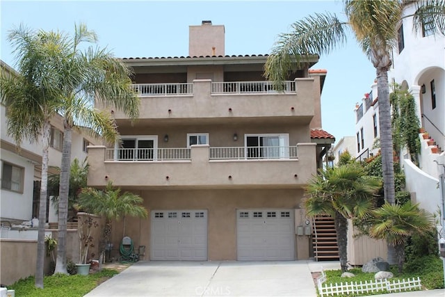 518 Avenida Victoria Unit A, San Clemente, CA 92672 - back of house with stucco siding, concrete driveway, a chimney, a garage, and a tiled roof