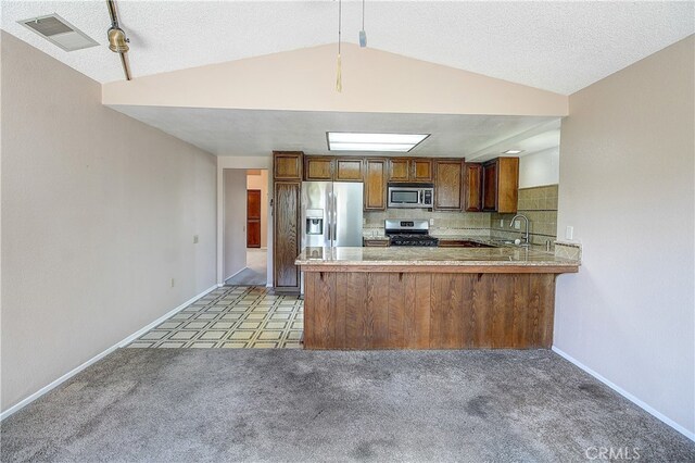 5050 Canyon Crest Dr Unit 5, Riverside, CA 92507 - kitchen featuring appliances with stainless steel finishes, brown cabinets, a peninsula, light countertops, and tasteful backsplash