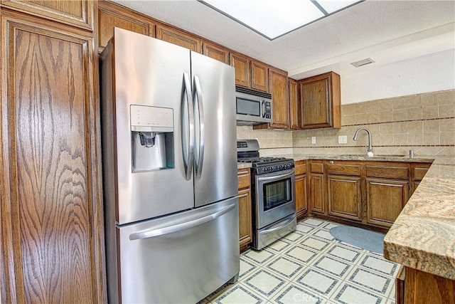 5050 Canyon Crest Dr Unit 5, Riverside, CA 92507 - kitchen featuring appliances with stainless steel finishes, brown cabinetry, light floors, and decorative backsplash
