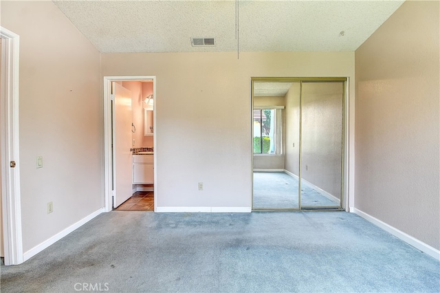 5050 Canyon Crest Dr Unit 5, Riverside, CA 92507 - unfurnished bedroom featuring a textured ceiling, carpet floors, a closet, and ensuite bathroom