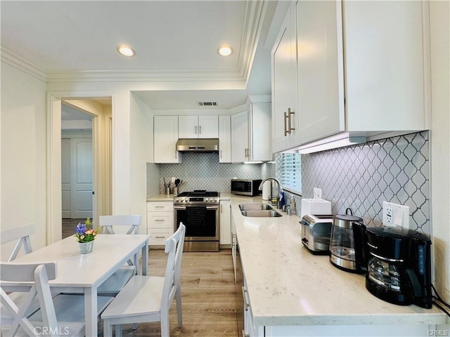 118 N Allen Ave Unit 2, Pasadena, CA 91106 - kitchen with stainless steel appliances, under cabinet range hood, crown molding, white cabinetry, and tasteful backsplash