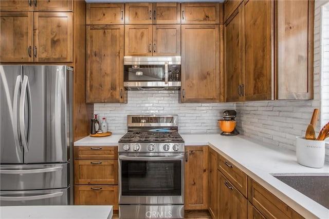 32425 Snowshoe Ln, Running Springs, CA 92382 - kitchen featuring stainless steel appliances, tasteful backsplash, brown cabinetry, and light countertops