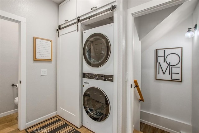 32425 Snowshoe Ln, Running Springs, CA 92382 - washroom with stacked washer and clothes dryer, a barn door, and light wood-type flooring