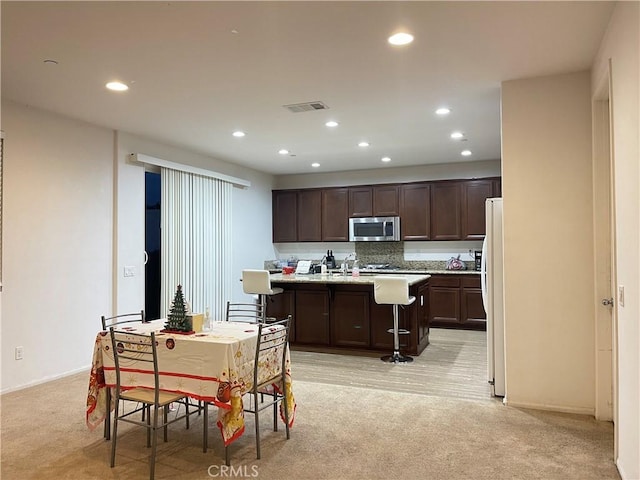 12639 Spruce Hill Rd, Moreno Valley, CA 92555 - kitchen with stainless steel microwave, light colored carpet, freestanding refrigerator, dark brown cabinets, and recessed lighting