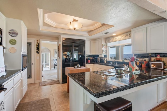 1524 Zutano Ln, Fallbrook, CA 92028 - kitchen with stovetop, black refrigerator, white cabinets, decorative backsplash, and a peninsula