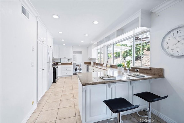 415 Buttonwood Dr, Brea, CA 92821 - kitchen featuring a peninsula, recessed lighting, white cabinetry, a breakfast bar area, and light tile patterned floors