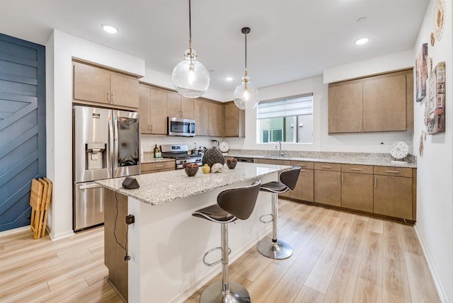 5261 Beachfront Cove St # 174, San Diego, CA 92154 - kitchen with appliances with stainless steel finishes, light wood-style flooring, a kitchen breakfast bar, a center island, and hanging light fixtures