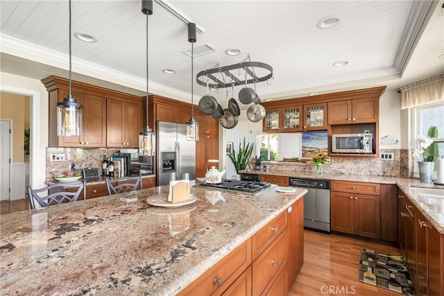 3602 E Ridgeway Rd, Orange, CA 92867 - kitchen featuring stainless steel appliances, brown cabinetry, hanging light fixtures, light wood finished floors, and light stone countertops