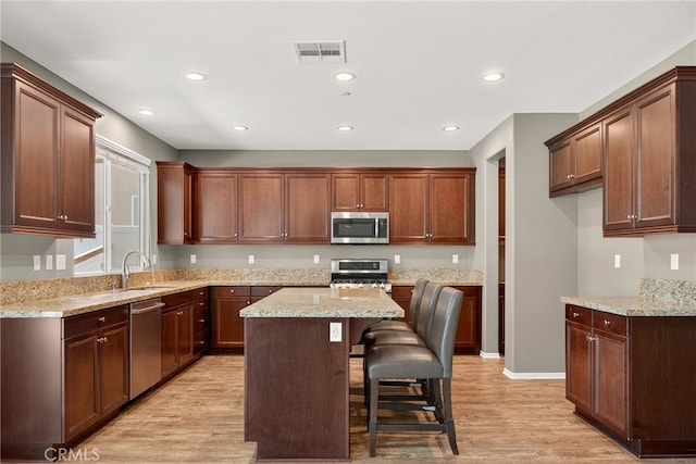 102 Mesa Ct, Calimesa, CA 92320 - kitchen with stainless steel appliances, light wood-style floors, recessed lighting, a kitchen island, and a breakfast bar