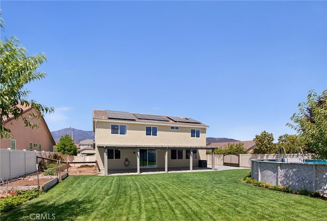 102 Mesa Ct, Calimesa, CA 92320 - back of property with roof mounted solar panels, a fenced backyard, a garden, stucco siding, and a patio