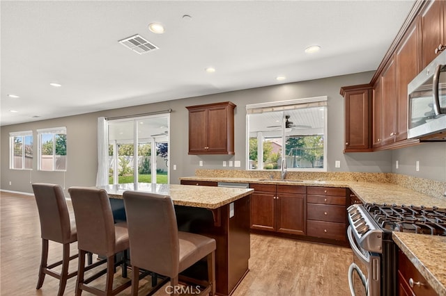 102 Mesa Ct, Calimesa, CA 92320 - kitchen featuring appliances with stainless steel finishes, light wood finished floors, a kitchen bar, plenty of natural light, and recessed lighting