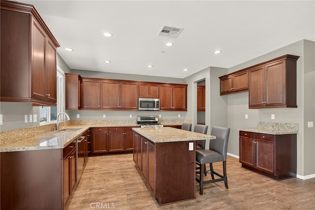 102 Mesa Ct, Calimesa, CA 92320 - kitchen with appliances with stainless steel finishes, light wood-style flooring, a center island, recessed lighting, and light stone counters