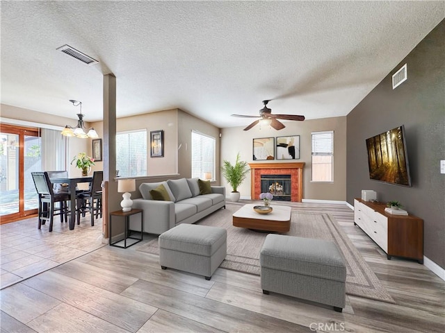 11700 White Pine Ct, Fontana, CA 92337 - living room featuring a ceiling fan, a glass covered fireplace, a chandelier, a textured ceiling, and light wood finished floors