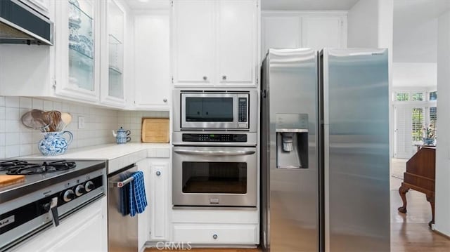 3620 Daffodil Ave Unit 31, Corona Del Mar, CA 92625 - kitchen featuring stainless steel appliances, light countertops, white cabinetry, tasteful backsplash, and exhaust hood