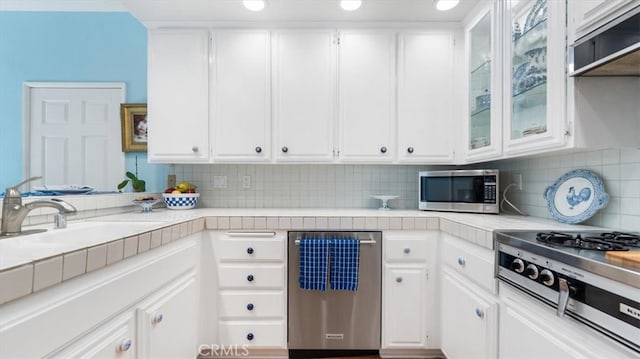 3620 Daffodil Ave Unit 31, Corona Del Mar, CA 92625 - kitchen with appliances with stainless steel finishes, light countertops, white cabinetry, backsplash, and glass insert cabinets