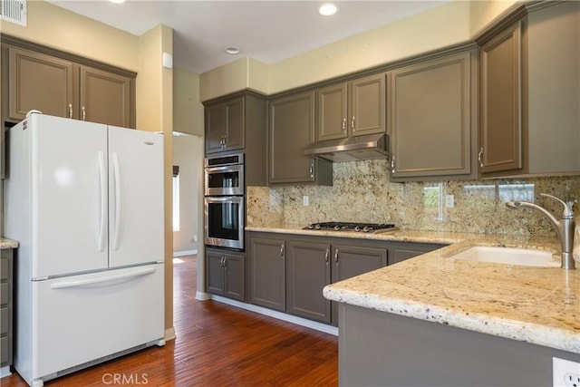 9320 Isaac Lord Dr, Rancho Cucamonga, CA 91701 - kitchen with appliances with stainless steel finishes, under cabinet range hood, dark wood-type flooring, light stone countertops, and backsplash
