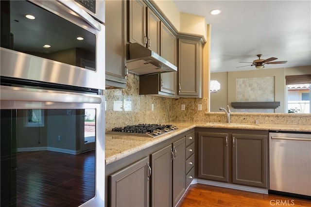 9320 Isaac Lord Dr, Rancho Cucamonga, CA 91701 - kitchen featuring appliances with stainless steel finishes, under cabinet range hood, a ceiling fan, wood finished floors, and tasteful backsplash