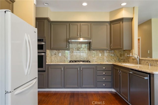 9320 Isaac Lord Dr, Rancho Cucamonga, CA 91701 - kitchen featuring stainless steel appliances, under cabinet range hood, dark wood-style flooring, light stone counters, and decorative backsplash