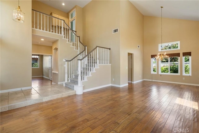 9320 Isaac Lord Dr, Rancho Cucamonga, CA 91701 - unfurnished living room featuring a chandelier, wood finished floors, a high ceiling, and stairs