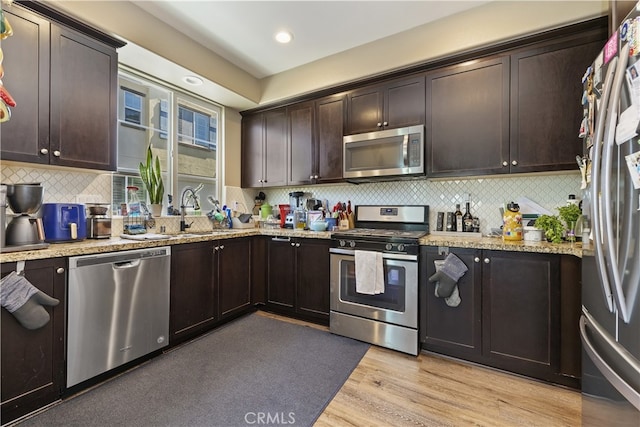 384 Ruby Red Ln, Upland, CA 91786 - kitchen with stainless steel appliances, dark brown cabinets, tasteful backsplash, light stone counters, and light wood-type flooring